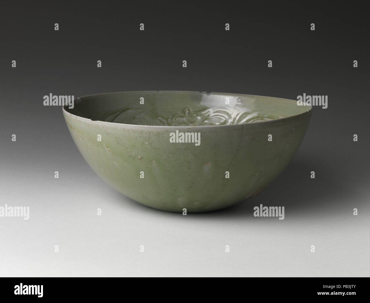 Bowl with Dragons among Waves. Culture: China. Dimensions: Diam. 10 5/8 in. (27 cm). Date: 10th century.  In the West, the term celadon is often used to describe ceramics covered with green glazes. In China, stoneware with celadon glaze is classified by the name of the kiln at which it was produced. This large bowl, with its three lively dragons frolicking in waves, comes from the eponymous Yue kilns in Zhejiang Province, which began making celadons as early as the second century B.C. Yue ware was used domestically as well as traded, particularly from the eighth to the eleventh century, when w Stock Photo