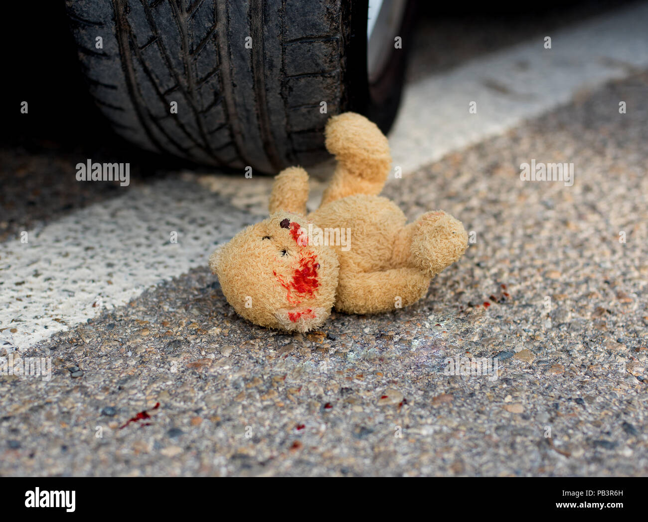 soft toy bear in the blood under the car wheels Stock Photo