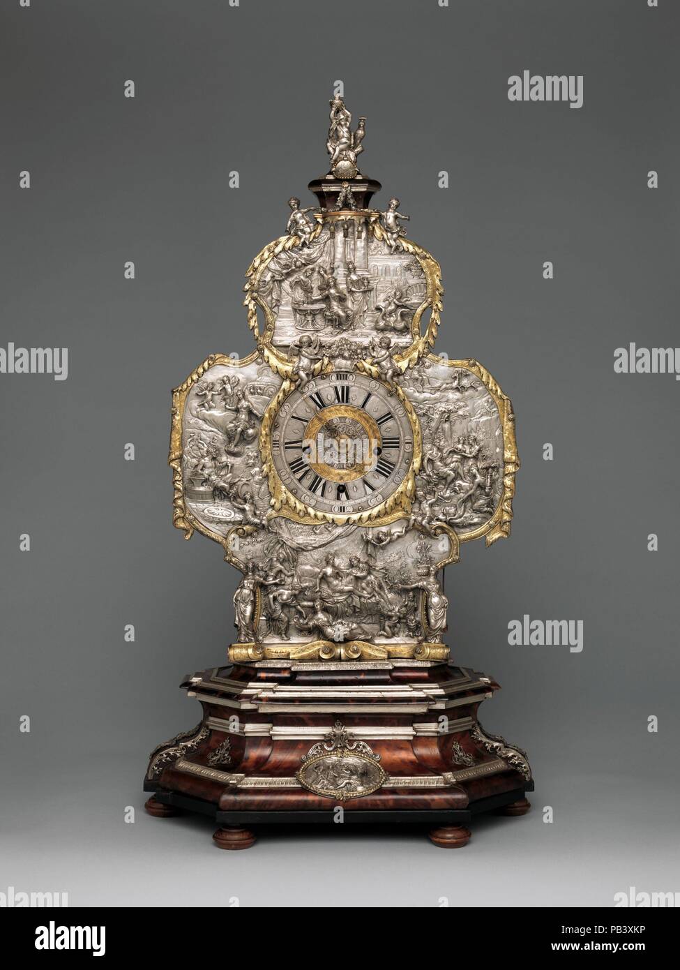 Mantel clock. Culture: German, Augsburg. Dimensions: Overall: 31 3/4 × 17 × 11 1/4 in. (80.6 × 43.2 × 28.6 cm). Maker: Clockmaker: Franz Xavier Gegenreiner (German, active 1760-70); Case maker: Johann Andreas Thelot (German, 1655-1734). Date: case ca. 1710, movement ca. 1760-70.  Thelot's ancestors were French Huguenots who emigrated from Dijon in 1585. He became one of the most celebrated goldsmiths in Augsburg, a city renowned for its metalwork in silver and silver gilt. The reliefs on this case depict the goddess Venus at her toilette (top), Venus and Diana (right), Venus and Mars (bottom), Stock Photo