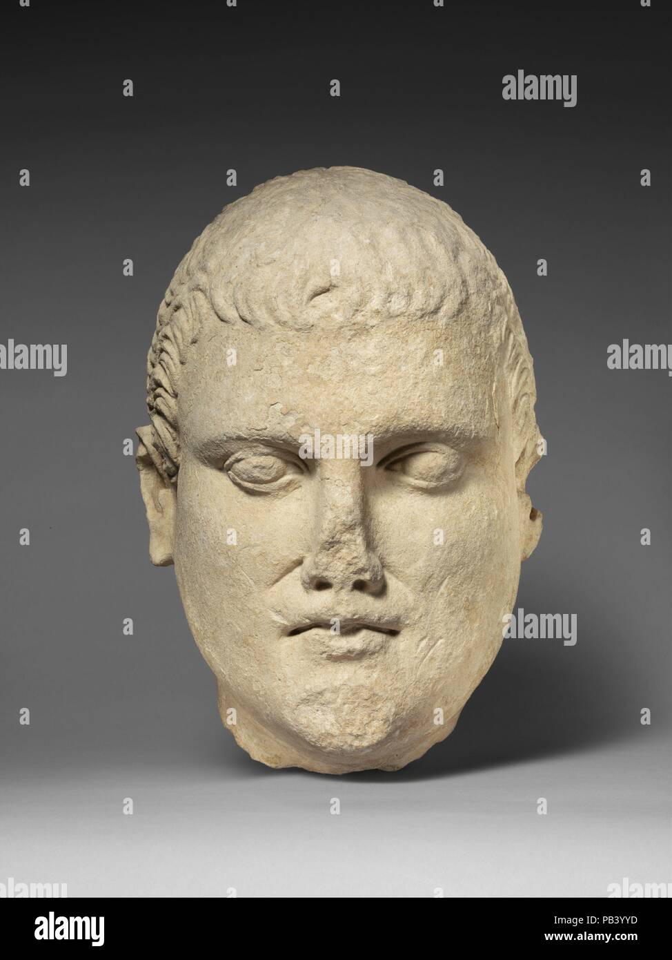 Limestone head of beardless male votary. Culture: Cypriot. Dimensions: 10 7/8 x 8 1/4 x 7 in.  (27.6 x 21 x 17.8 cm). Date: early 1st century B.C..  The lower portion of the face is heavy, the chin juts out. The half-open mouth has a severe expression. The small ears are carefully rendered. Museum: Metropolitan Museum of Art, New York, USA. Stock Photo