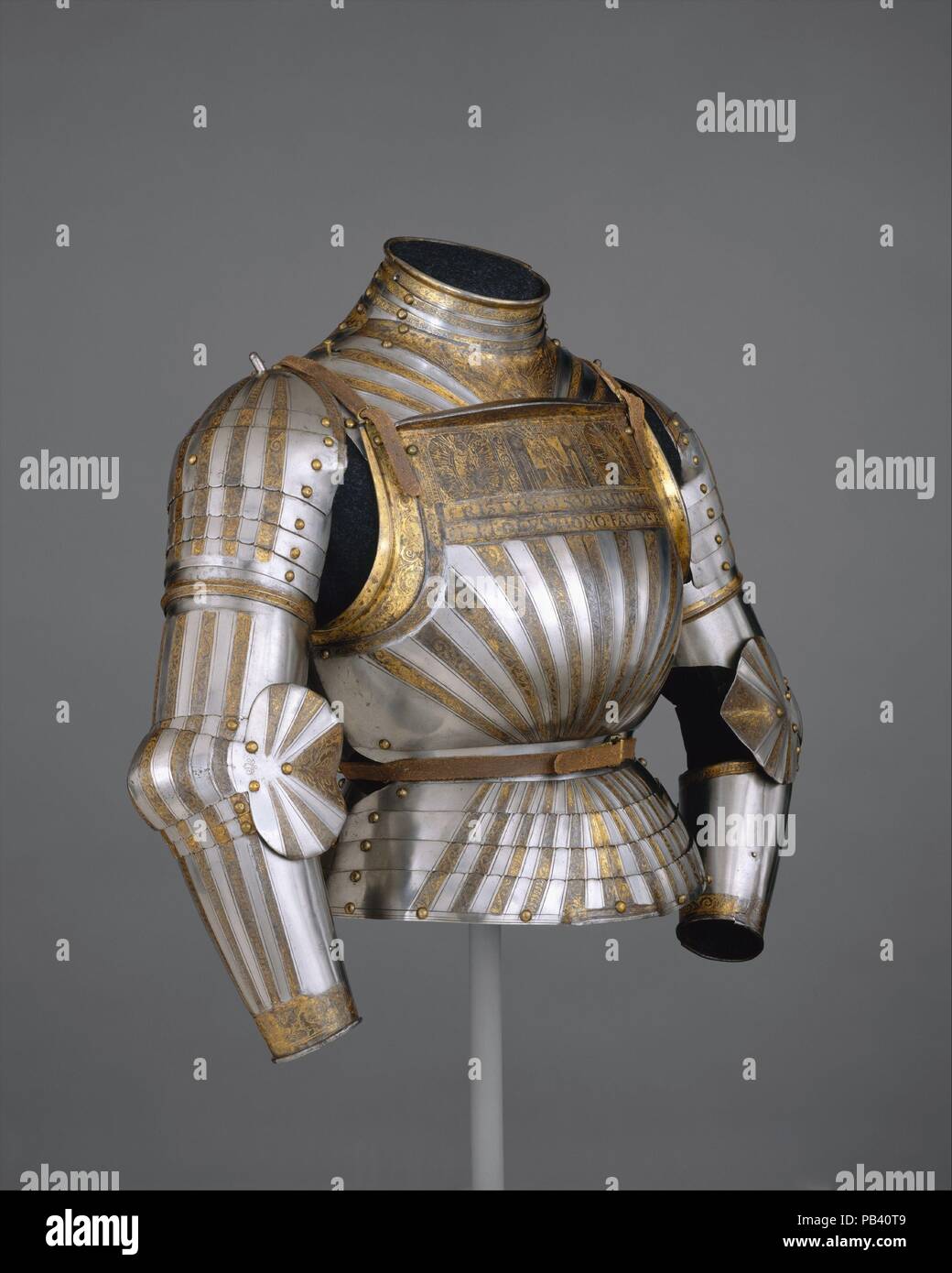 Elements of a Light-Cavalry Armor. Culture: Italian, Milan. Dimensions: Wt. 19 lb. 13 oz. (8987 g). Date: ca. 1510.  This is a rare example of Italian armor decorated with fluted surfaces in the German fashion. Its etched and richly gilt decoration is derived from Christian symbolism and the Bible. The band across the top of the breastplate depicts the Virgin and Child in the center, Saint Paul on the right, and Saint George on the left. A Latin inscription below reads, CHRISTVS RES VENIT IN PACE ET DEVS HOMO FACTVS ES (Christ the King came in peace and God was made man). Another inscription,  Stock Photo