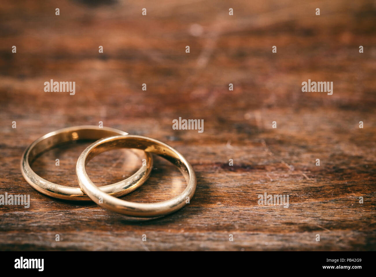 A pair of golden wedding rings on wooden background, copy space Stock Photo