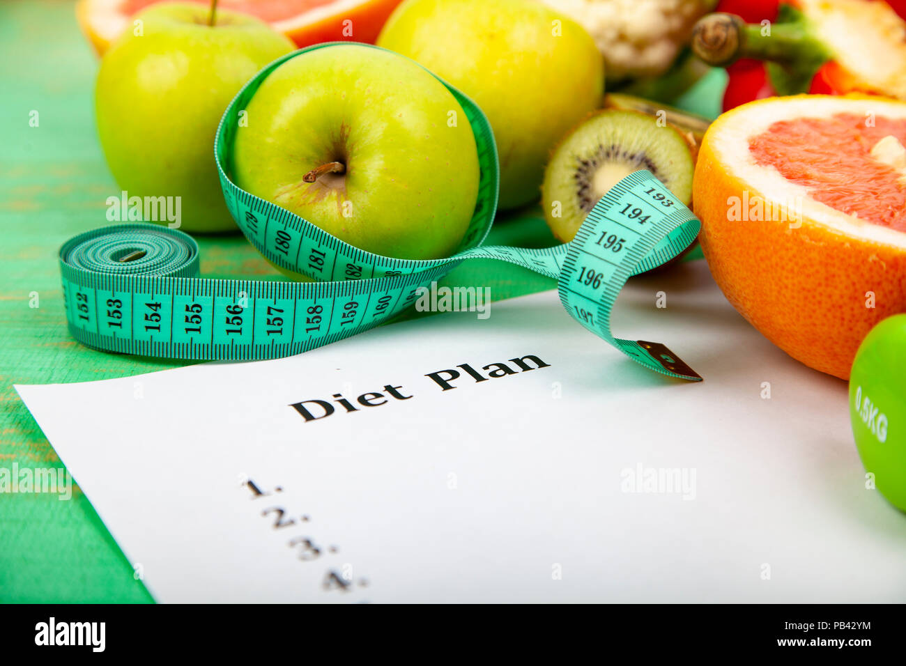 Food and sheet of paper with a diet plan on a green wooden background ...
