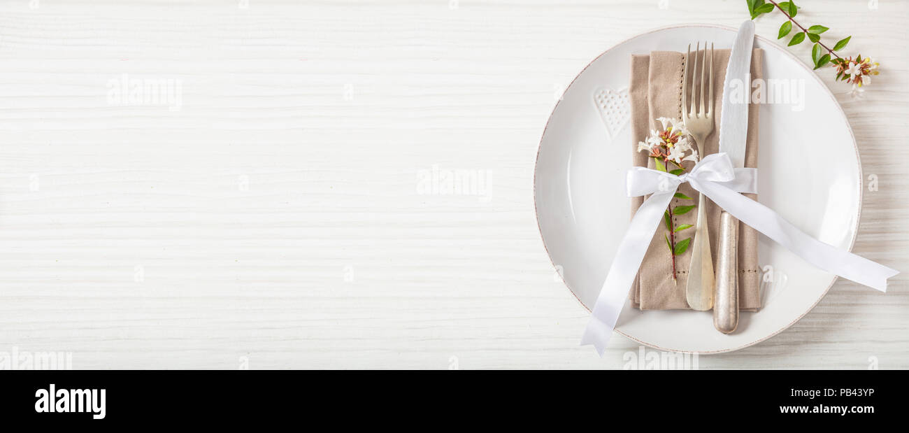 Holiday dinner. Table place setting with empty plates, silver fork and knife, banner, copy space Stock Photo