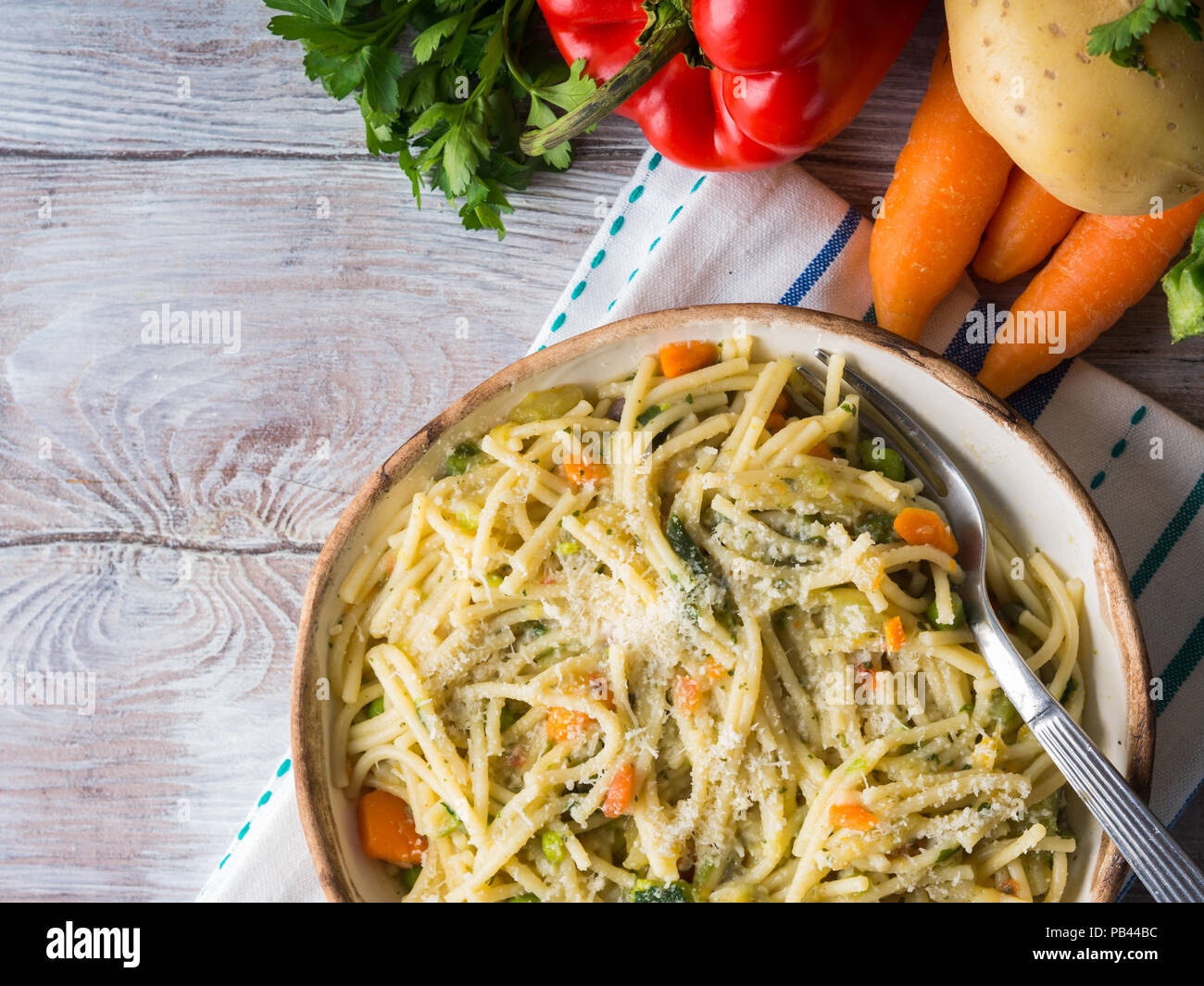 Spaghetti cooked in vegetable broth sauce on rustic wooden background