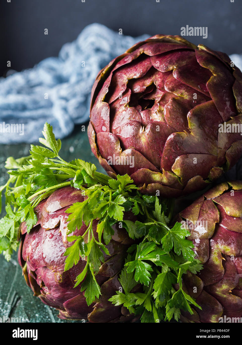Raw artichokes with parsley herb on dark background Stock Photo Alamy
