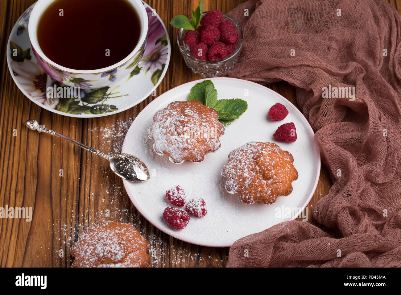 Capcake with raspberries and sugar powder on the table with tea teapot Stock Photo