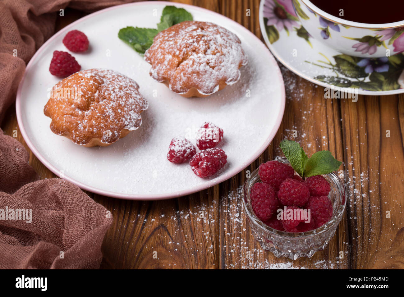 Capcake with raspberries and sugar powder on the table with tea teapot Stock Photo