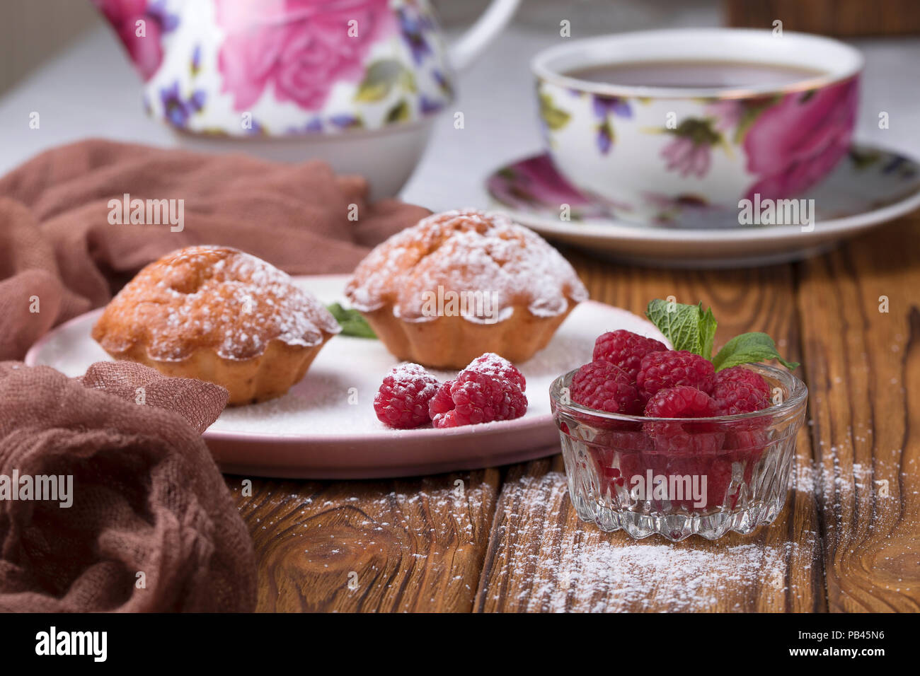 Capcake with raspberries and sugar powder on the table with tea teapot Stock Photo