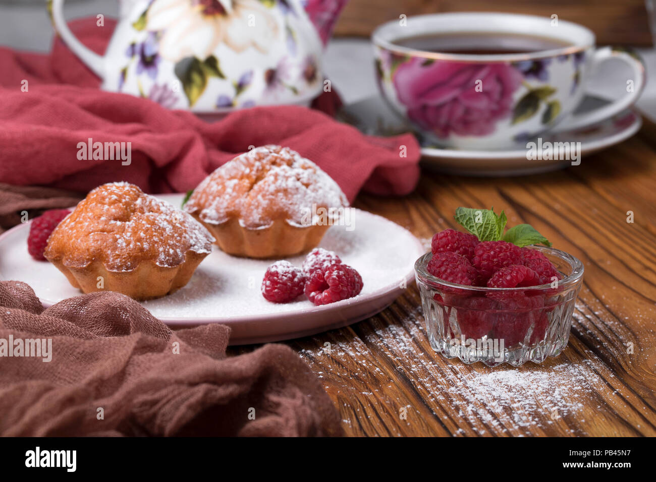 Capcake with raspberries and sugar powder on the table with tea teapot Stock Photo