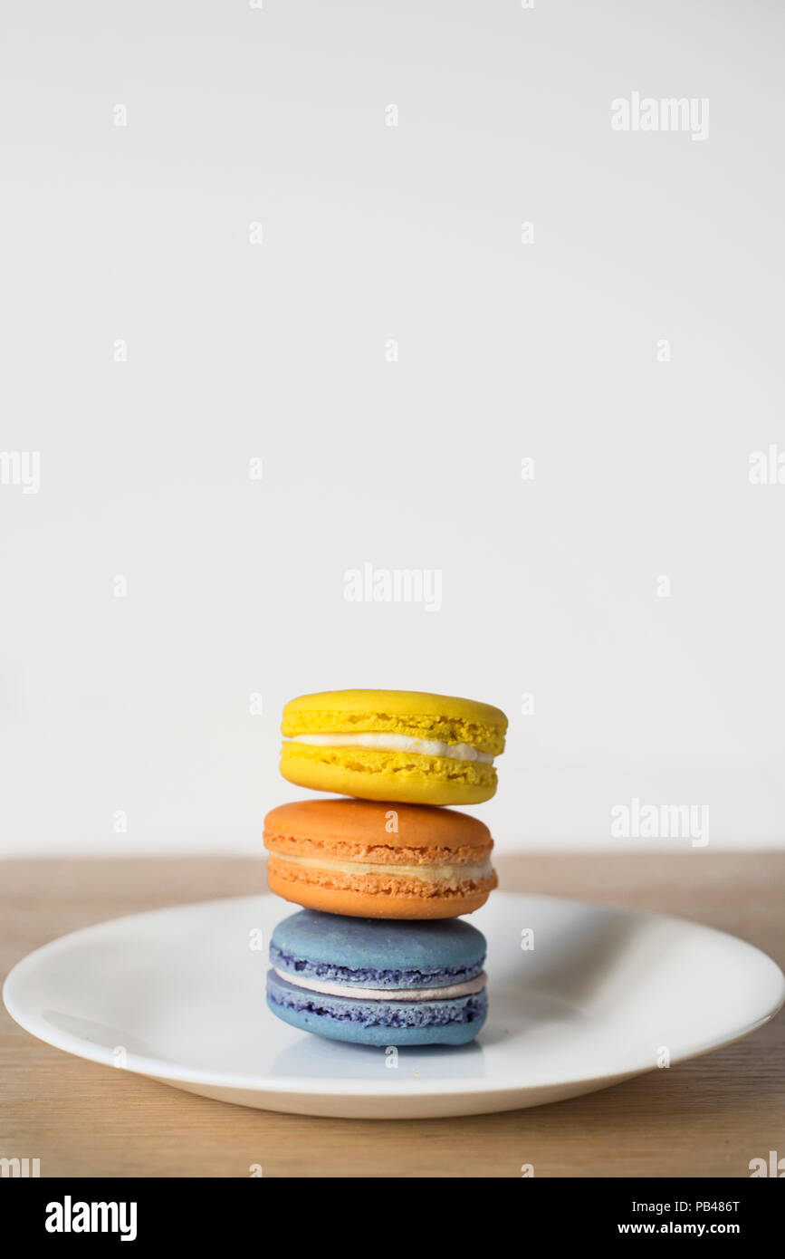 A Pile-Up of Macarons in Three Colors - Bright Baked Goods Trio on a Plate Stock Photo