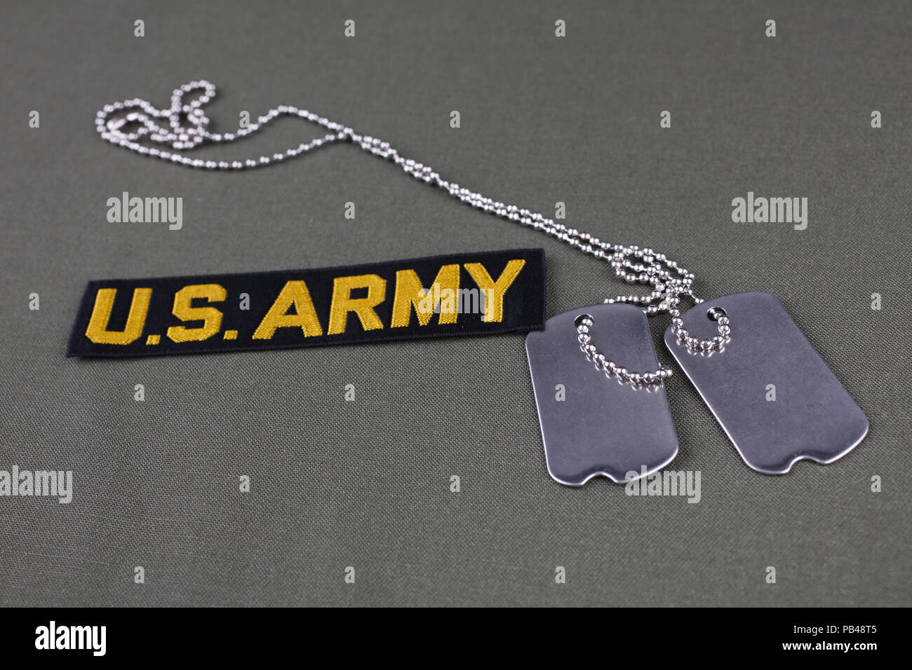 U.S. Army Branch Tape with dog tags on olive green uniform background