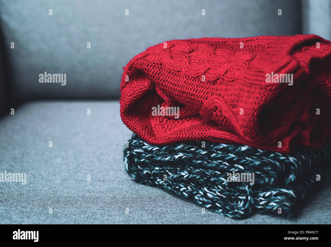 horizontal, warm sweaters on grey couch, seasonal concept, autumn fall winter outfit, cold weather Stock Photo