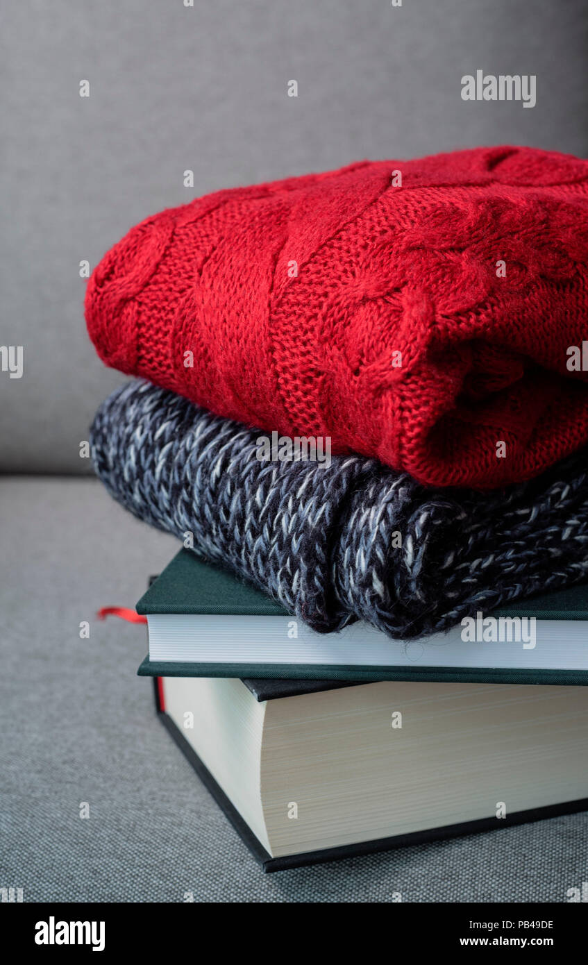 hugge autumn winter concept, red sweaters and books on grey background, cold weather, cozy home Stock Photo