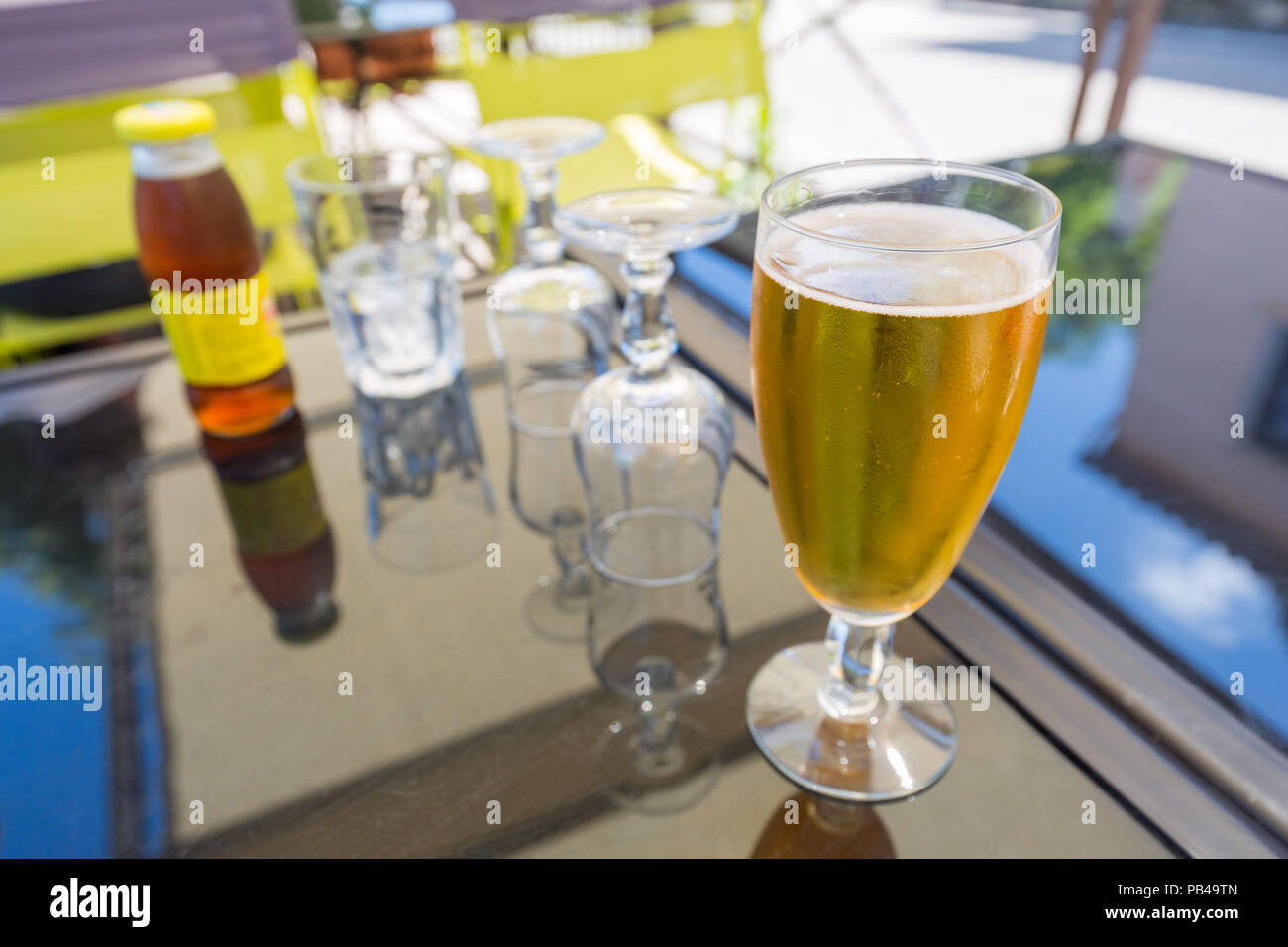Fresh beer and empty glasses on  an outdoor glass table in a restaurant Stock Photo