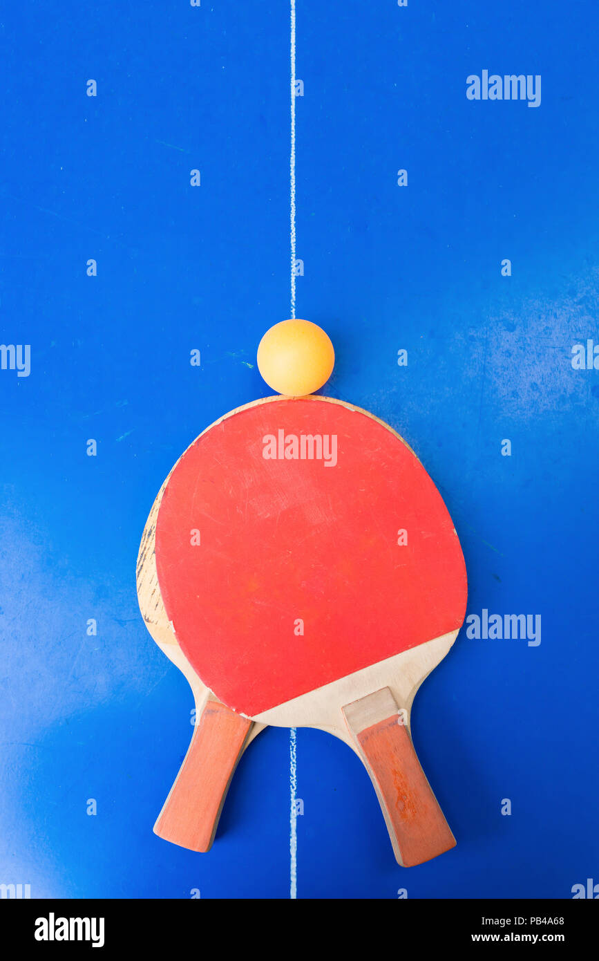 pair of old pingpong rackets and a ball on a blue pingpong table Stock Photo