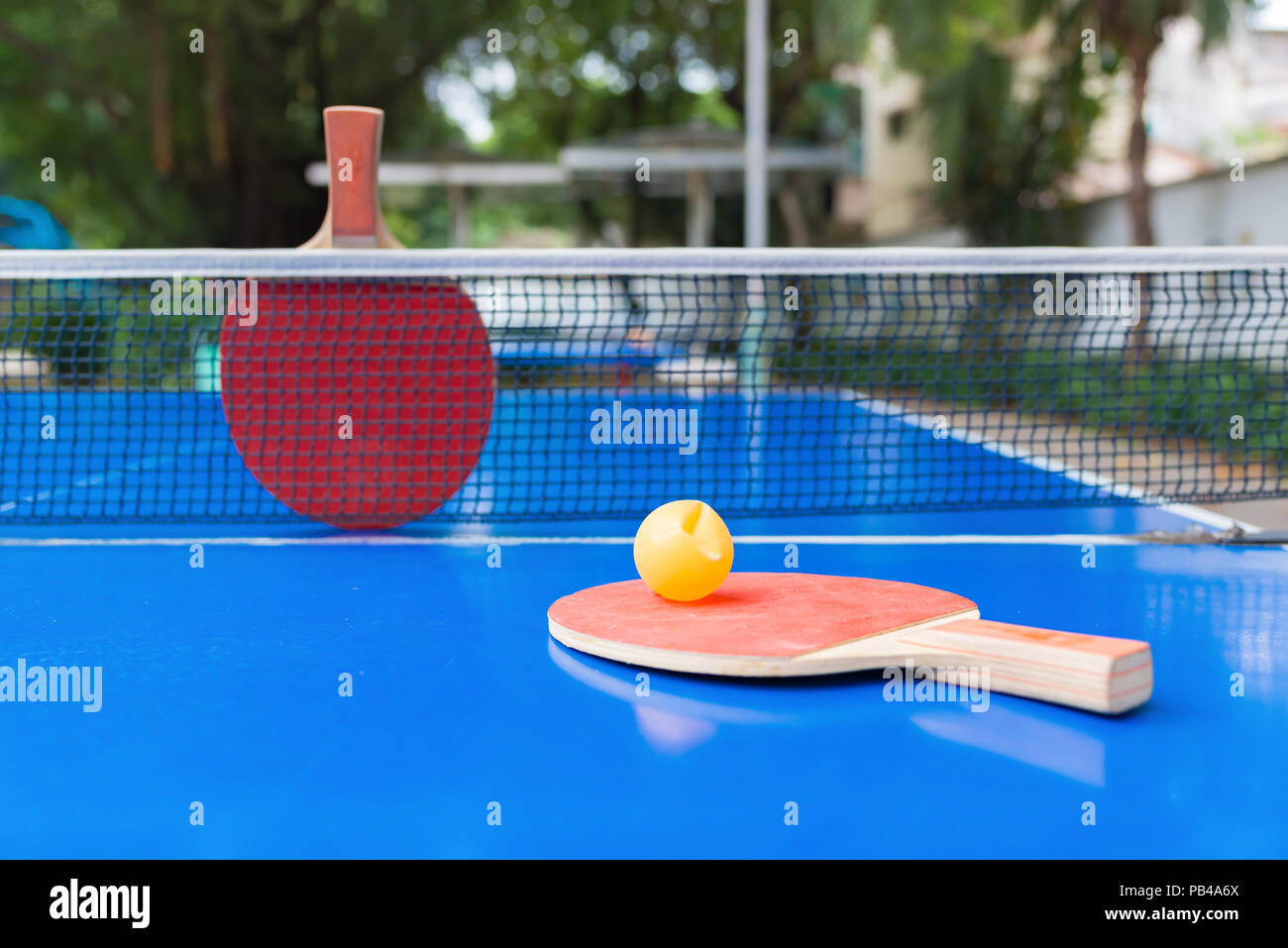 pingpong rackets and ball and net on a blue pingpong table Stock Photo