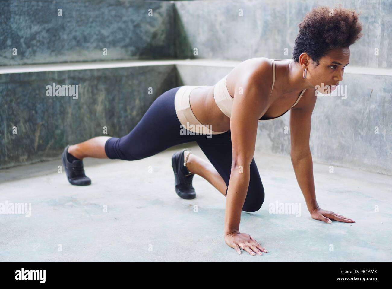 Melanesian pacific islander athlete girl with afro performing exercising routines plank with twist, one hand raised Stock Photo