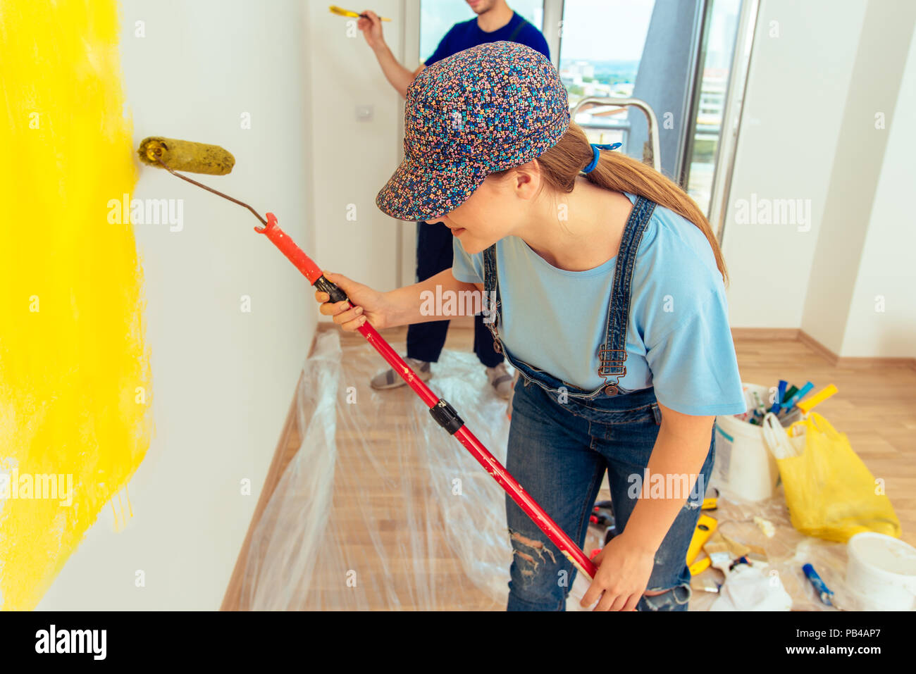 Couple decorating room using paint rollers and paintbrush on wall Stock Photo