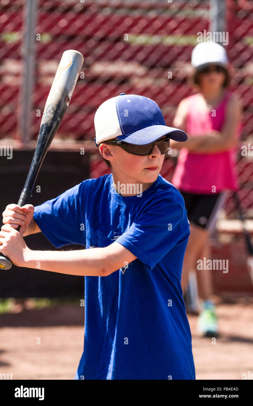 12 Year old boy, in batting stance, close up, wearing hat, blue jersey and red shoes, sunglasses.Model Relese #105 Stock Photo