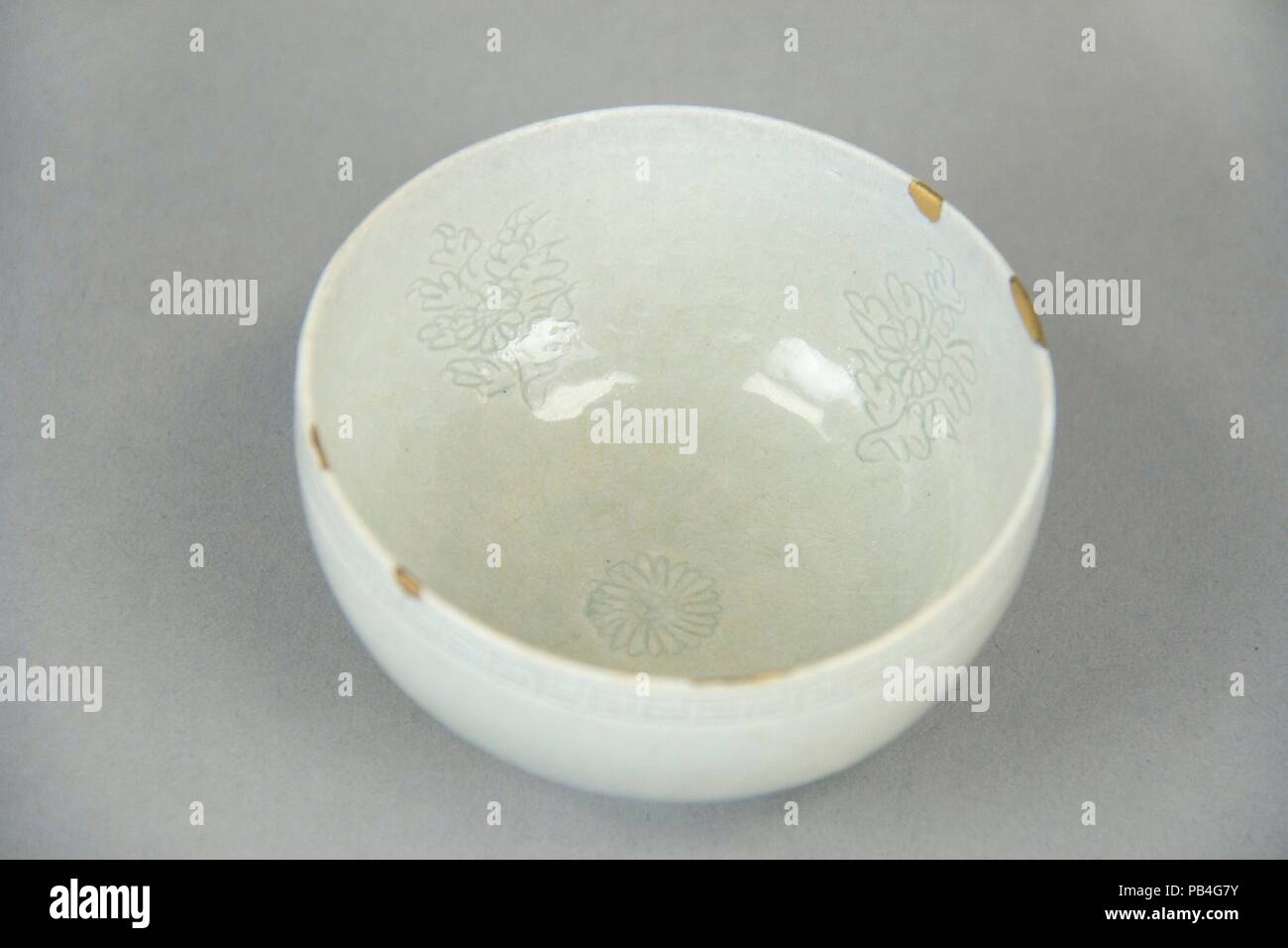 Small bowl decorated with chrysanthemum. Culture: Korea. Dimensions: H. 1 3/4 in. (4.4 cm); Diam. 3 5/16 in. (8.4 cm); Diam. of foot 1 5/8 in. (4.1 cm). Date: 12th century.  This delicate bowl exemplifies white ware of the Goryeo period--what might be termed 'soft' porcelain because of the type of clay--of which there was limited production. Porcelain became the main type of ceramic on the peninsula from the fifteenth century under the Joseon dynasty. Museum: Metropolitan Museum of Art, New York, USA. Stock Photo