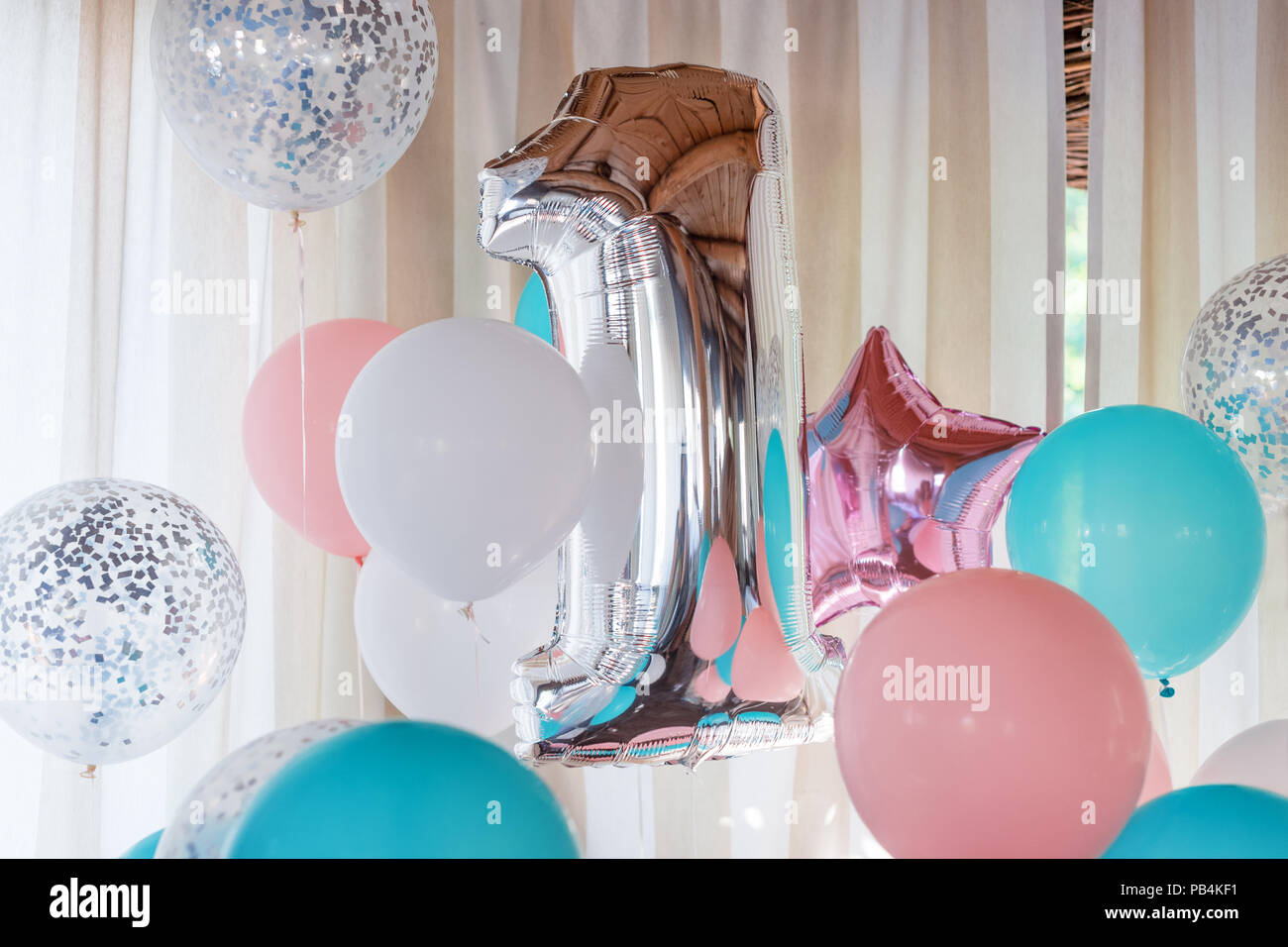 Pink, silver and blue inflatable balloons on ribbons - number 1. Decorations for birthday party. Metallic design balloon Stock Photo
