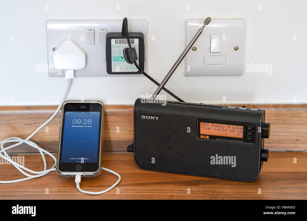Apple iPhone SE being charged up next to a DAB radio Stock Photo Alamy