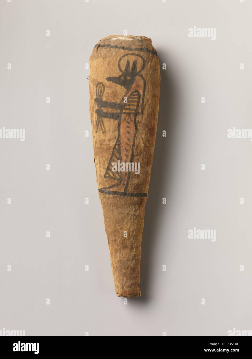Sacred animal mummy in the form typical of a wrapped ibis, decorated with a figure of Duamutef. Dimensions: H. 40.5 cm (15 15/16 in.); W. 10.2 cm (4 in.); D. 8.7 cm (3 7/16 in.). Date: ca. 400 B.C.-100 A.D..  Animal cults   The Egyptians considered certain individual animals to be living manifestations of a god, such as, since earliest times, the Apis bull . Those individuals were duly mummifed when they died and buried for eternal life, then replaced by another single living manifestation. During the first millennium BC, many multiples of animals associated with certain gods were specially ra Stock Photo
