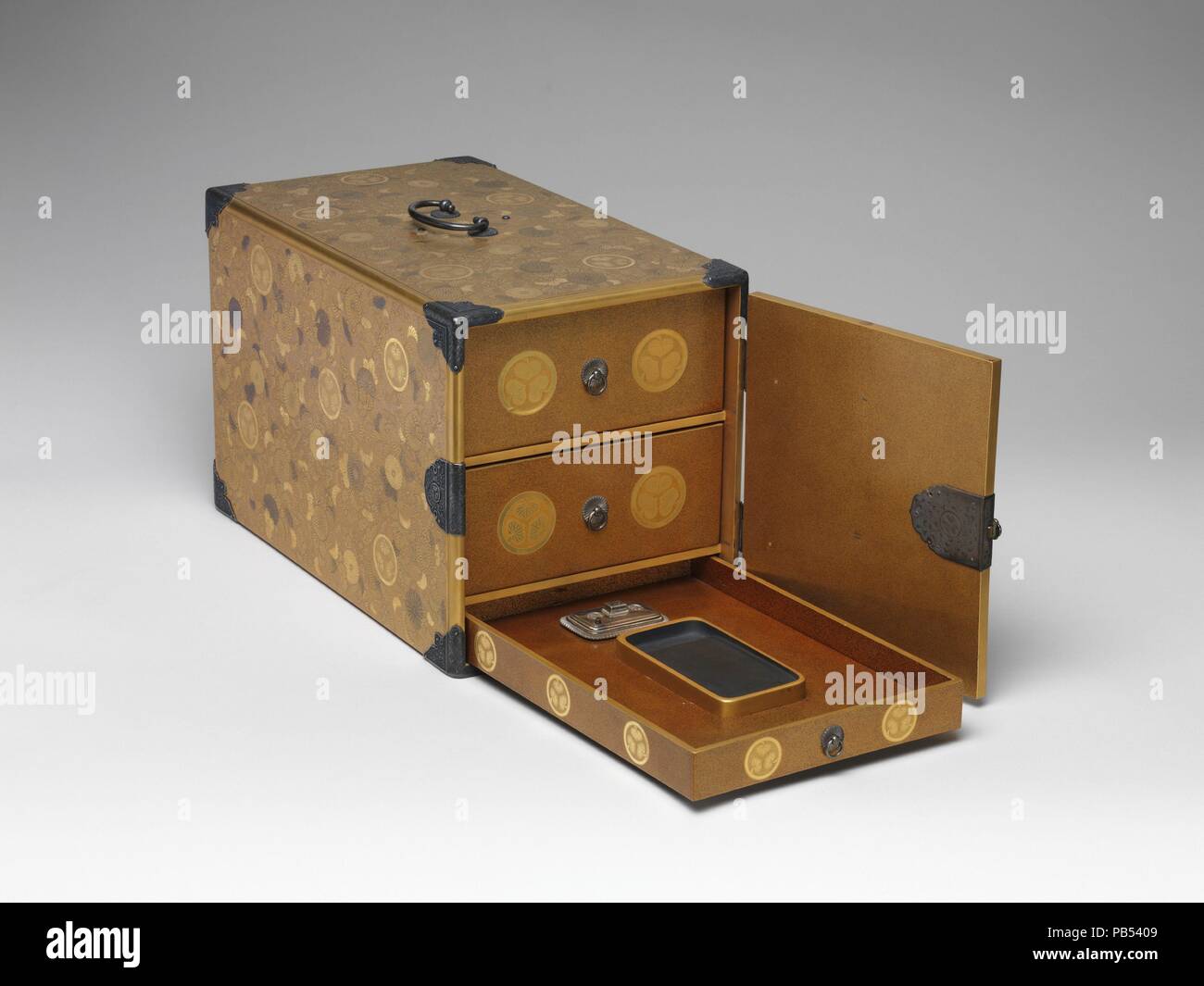 Portable Writing Cabinet with Tokugawa Family Crests, Chrysanthemums, and Foliage Scrolls. Artist: Koami School. Culture: Japan. Dimensions: H. 9 in. (22.9 cm); W. 8 1/2 in. (21.6 cm); D. 14 5/8 in. (37.1 cm). Date: late 17th century.  This portable writing box has three drawers; the two upper ones are for paper and documents, while the one at the bottom holds the inkstone, water dropper, and brushes. The cabinet is elaborately decorated with the highest quality maki-e ('sprinkled pictures'). It was produced for the Tokugawa family in one of their official maki-e workshops, probably that of th Stock Photo