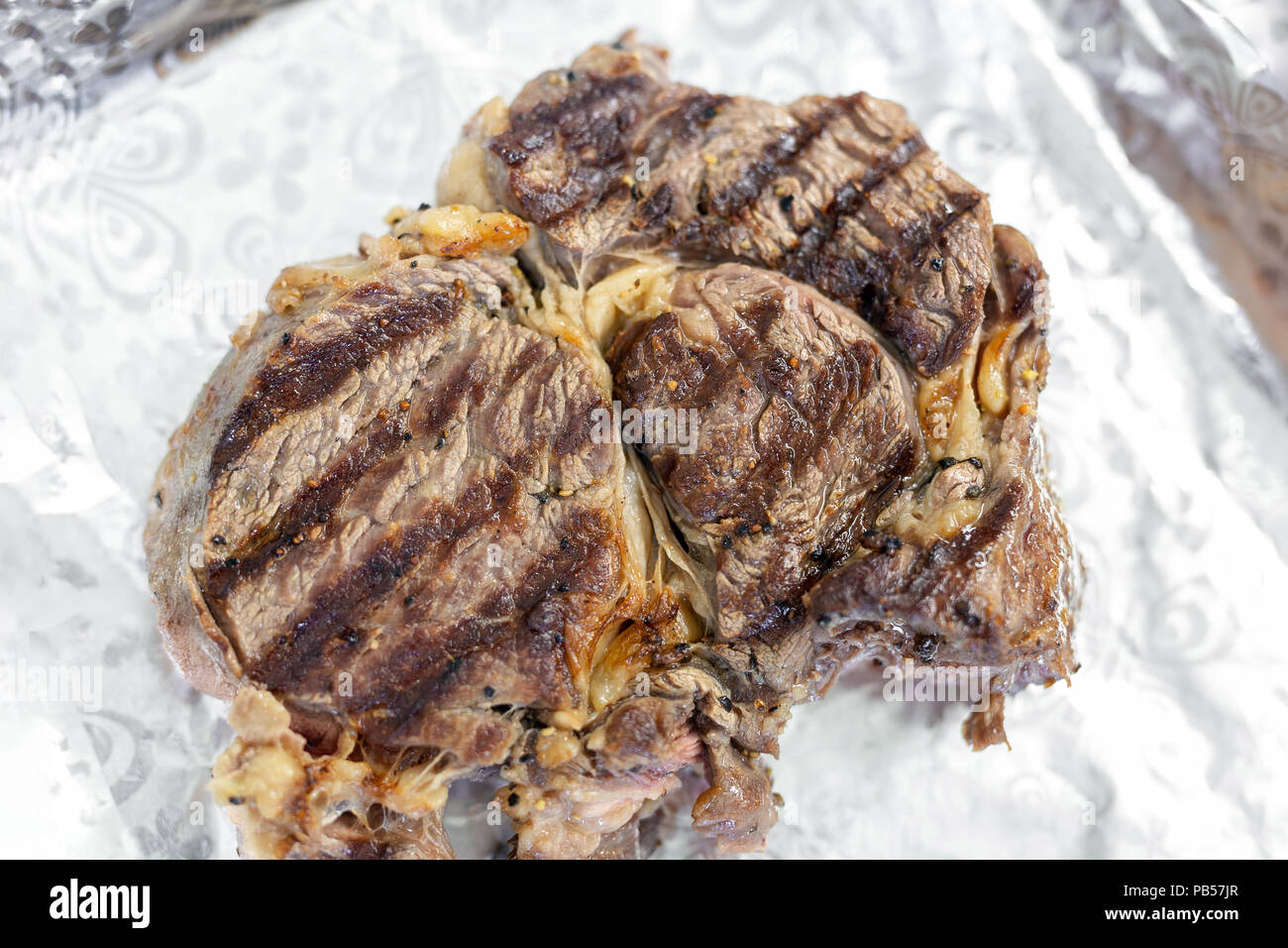 Closeup tasty juicy rib eye steak on aluminium foil. . Organic beef meat seasoned with ground