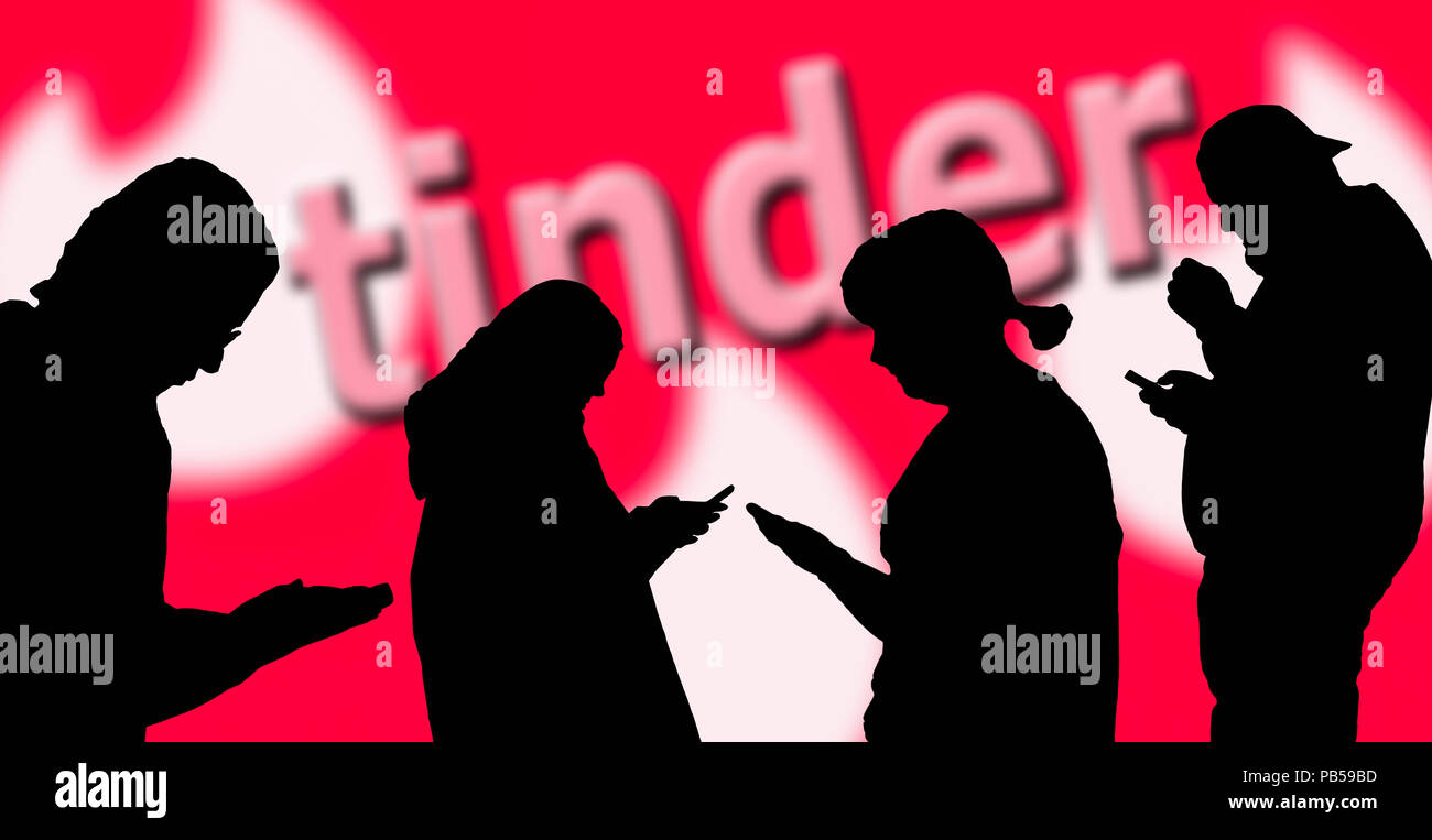 Silhouettes of a group of people using the Tinder dating app on smartphones. Tinder social media. Stock Photo