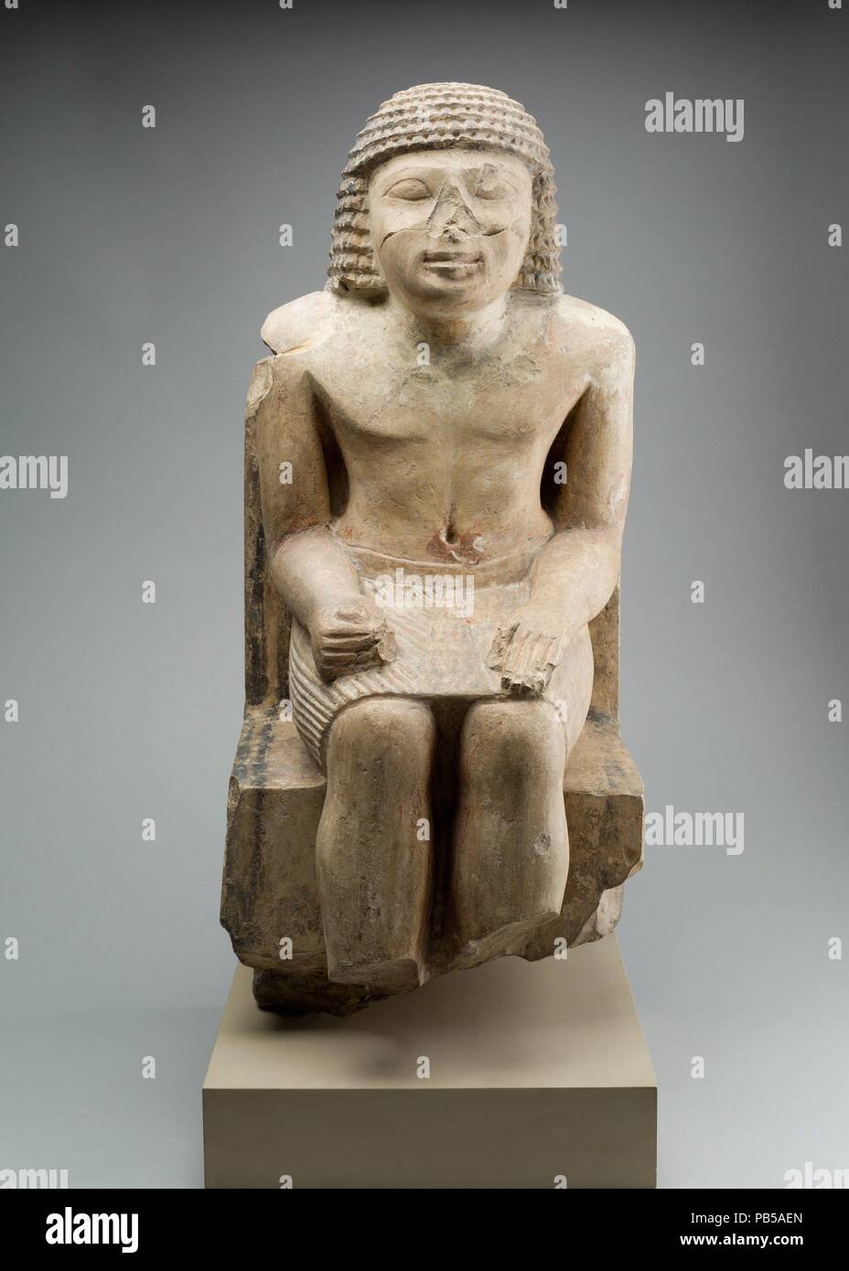 Seated Statue of the Nomarch Idu II of Dendera. Dimensions: H: 60.5 cm (23 13/16 in.). Dynasty: Dynasty 6. Reign: Reign of Pepi II. Date: ca. 2246-2152 B.C..  Discovered in his mastaba tomb at Dendera, this statue represents the nomarch (governor) of a province of Upper Egypt during the late Old Kingdom. This man, Idu II, wielded considerable power during the long reign of Pepi II, the last king of Dynasty 6. Created by a provincial artist, the figure has very large eyes and somehwat unconvential proportions, and is seated on a high-backed chair instead of the more common block seat. He wears  Stock Photo
