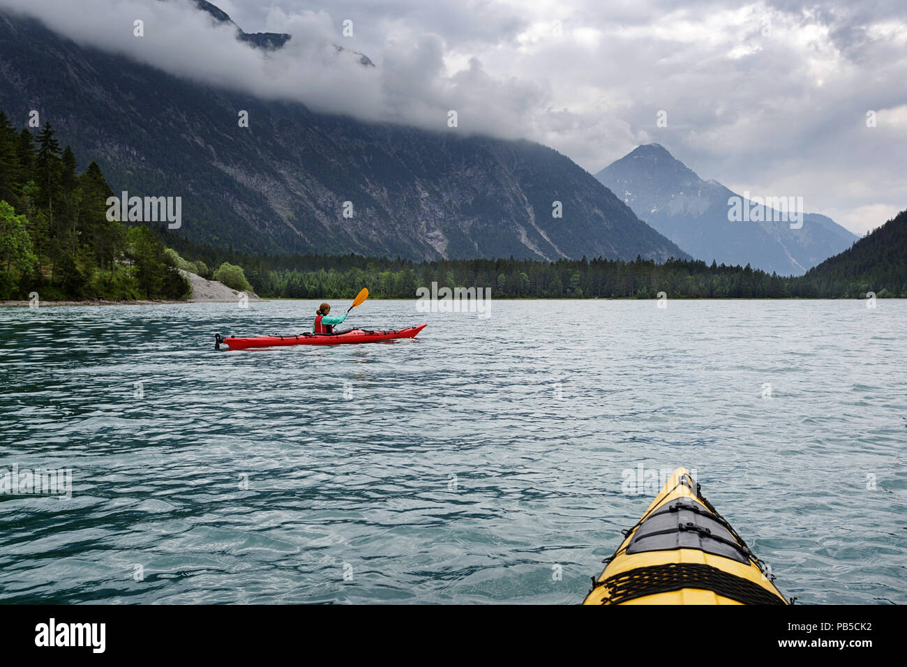 Two kayaks paddling on Plansee, Woman in red kayak kayaking on Plansee, Austria Stock Photo