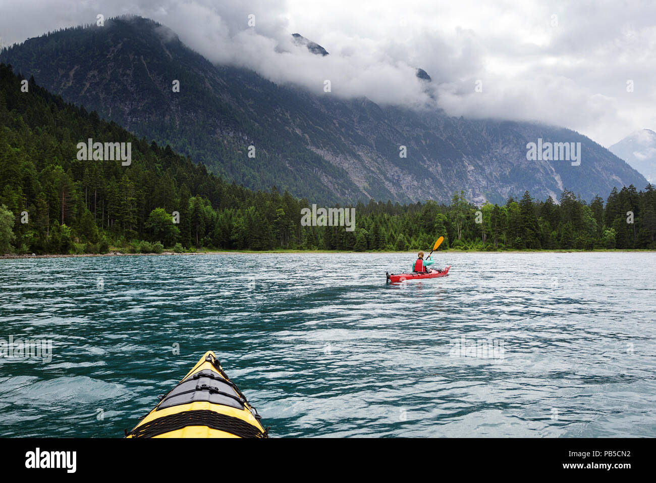 Two kayaks paddling on Plansee, Woman in red kayak kayaking on Plansee, Austria Stock Photo
