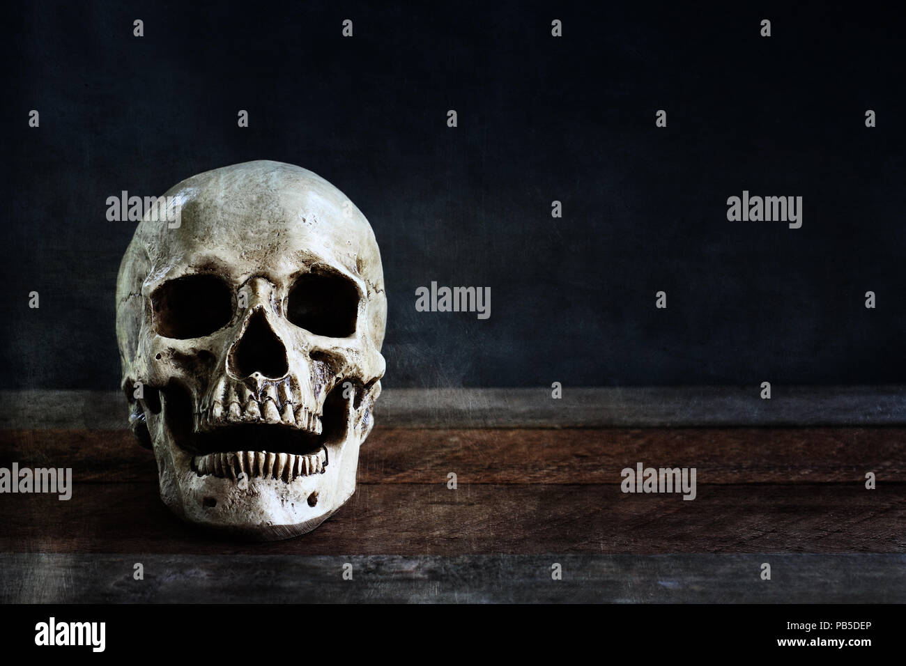Halloween human skull on an old wooden table in front of black background with free space for text. Stock Photo