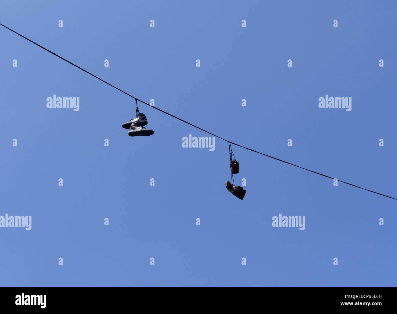 Two pairs of trainers hanging from a wire Stock Photo