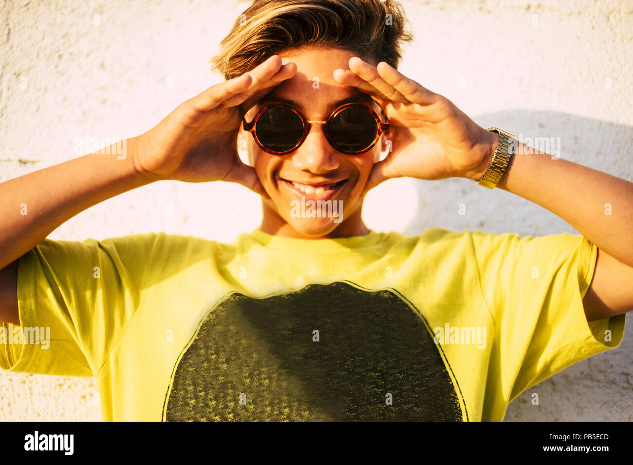 beautiful and wonderful nice young model 14 years old pose and smile to the camera under the sunlight. vacation and happiness concept wih blonde boy Stock Photo