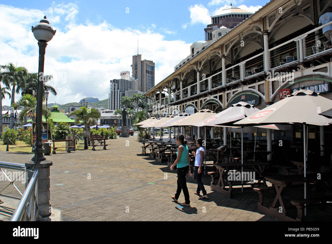 Restaurants at the Caudan Waterfront with the skyline of Port Louis in the background - Port Louis, Mauritius Stock Photo