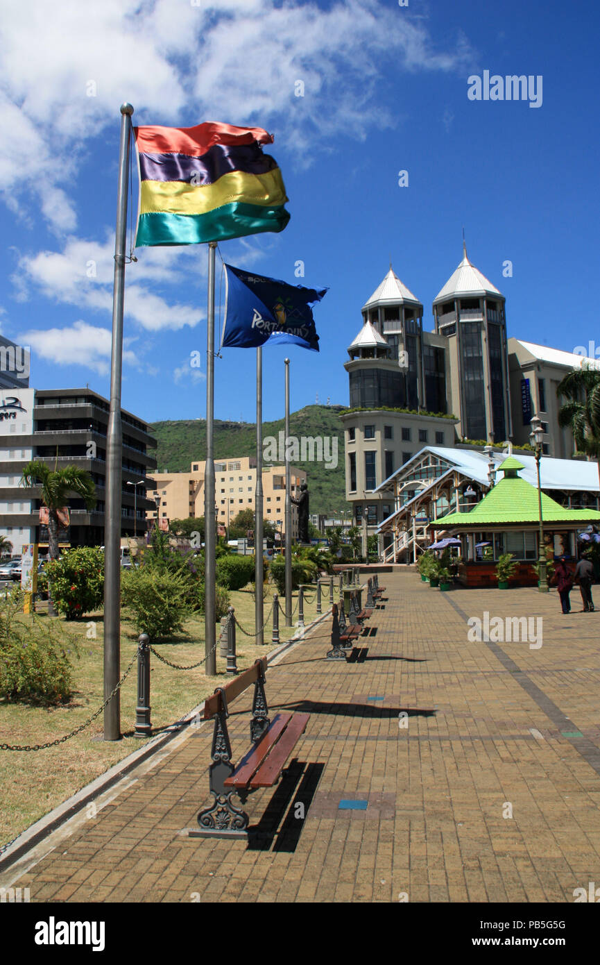 Flag of Mauritius flying in the wind at the palm tree lined main square in front of the Caudan Waterfront in Port Louis, Mauritius Stock Photo