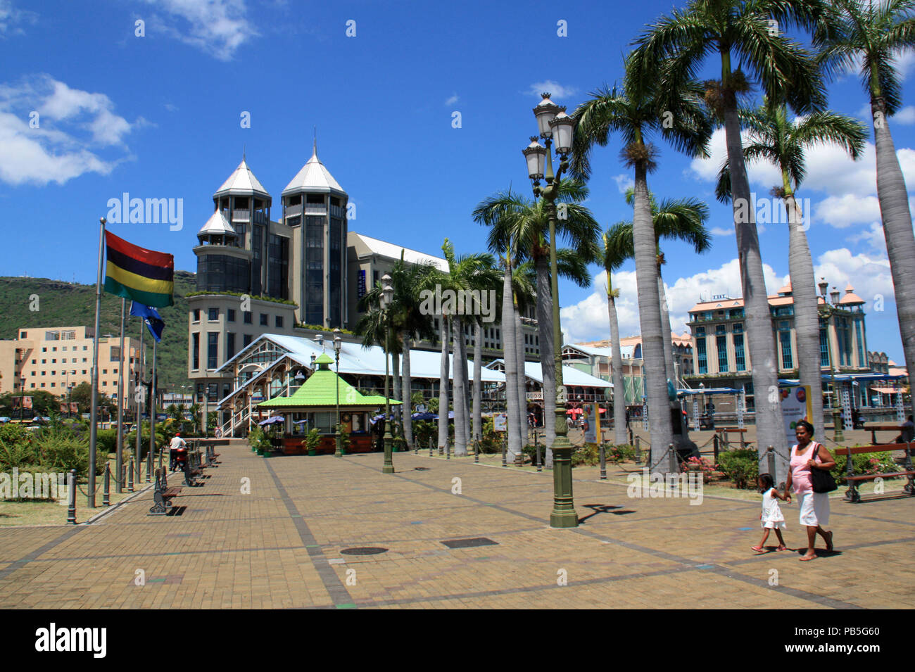 Flag of Mauritius flying in the wind at the palm tree lined main square in front of the Caudan Waterfront in Port Louis, Mauritius Stock Photo