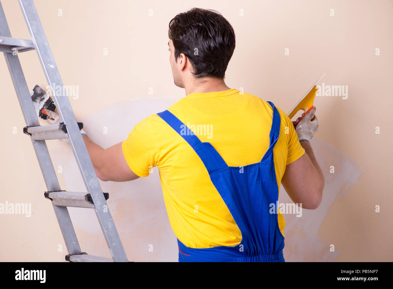 Young contractor employee applying plaster on wall Stock Photo