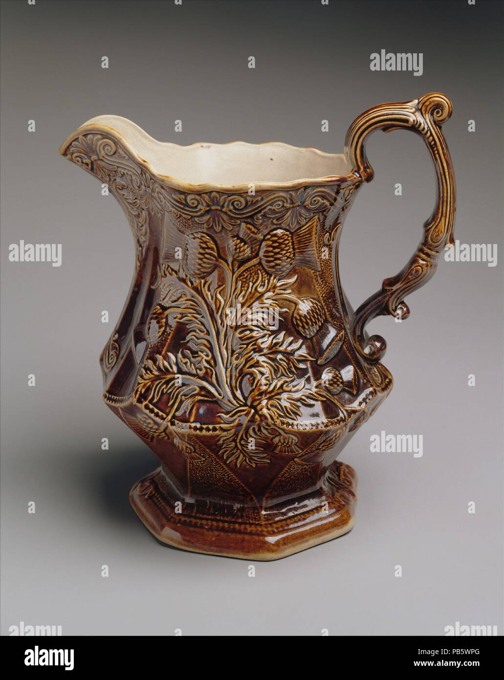 Pitcher. Culture: American. Dimensions: 9 5/8 x 9 1/8 x 7 in. (24.4 x 23.2 x 17.8 cm). Manufacturer: American Pottery Manufacturing Company (1833-ca. 1854). Date: 1833-50.  In 1828 two Scotsmen David and James Henderson took over the defunct Jersey Porcelain and Earthenware Company in Jersey City, New Jersey, to fabricate fine stonewares that resembled those made in England. Such mid-range wares were imported into America in large quantities. The Jersey City factory relied heavily on English workers, designs and factory practices.  Many of the firm's products, pitchers, in particular, virtuall Stock Photo