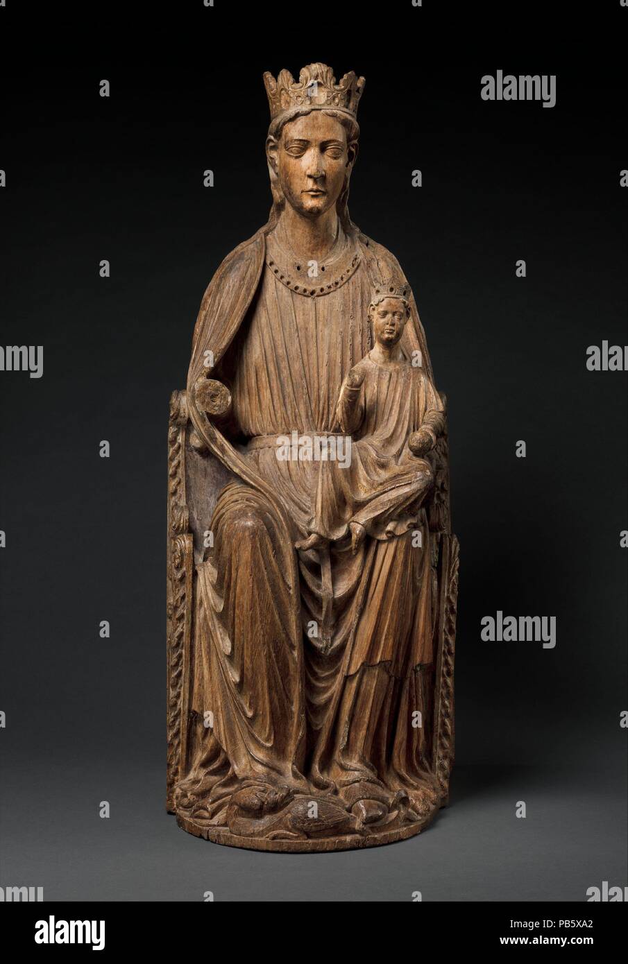 Enthroned Virgin and Child. Culture: North French. Dimensions: Overall: 48 1/2 x 20 1/4 x 19in. (123.2 x 51.4 x 48.3cm). Date: ca. 1210-20.  Crowned as the Queen of Heaven, Mary is seated on a richly ornamented throne, while the infant Jesus holds an orb or apple and blesses. Mary also tramples a dragon in triumph--a visual reference to the Book of Genesis (3:15), in which God declares to the serpent, 'I will put enmity between thee and the woman.' The fluid drapery style is a hallmark of northern sculpture about 1200. Museum: Metropolitan Museum of Art, New York, USA. Stock Photo