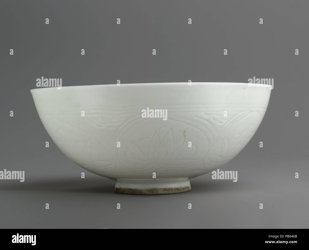 Bowl with Incised Lotus Flowers. Dimensions: H. 3 3/8 in. (8.6 cm)  Diam. 7 7/8 in. (20 cm). Date: second half 17th century or later.  This bowl along with a bottle (91.1.131) are part of a group of Iranian ceramics known as Gombroon ware, named after a trading post on the south coast of Iran. Ideally situated, the port was frequented by both the Dutch and English East India Companies and served as an entrepot for ceramics and other luxury goods into Europe. The style of Gombroon ceramics and their role in international trade reflect the significant artistic, cultural, and economic ties that e Stock Photo