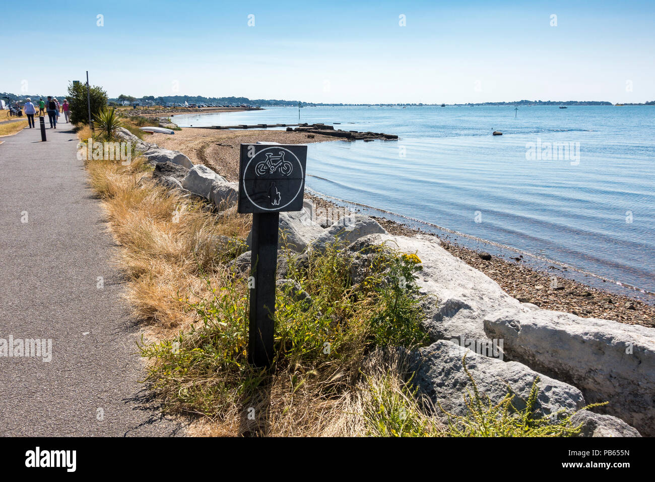 A footpath and bicycle pathway with a signpost alongside Poole Harbour, Dorset, United Kingdom Stock Photo