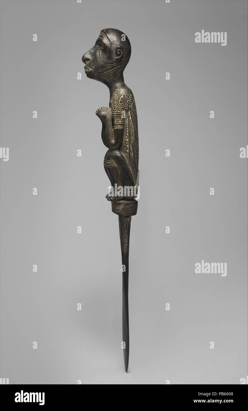 Lime Spatula. Artist: Mutuaga (1860-1920). Culture: Massim. Dimensions: H. 24 1/2 in. (62.2 cm). Date: 1900-1910.  The identities of the individuals who created the vast majority of Oceanic sculpture  remain unknown. A notable exception is Mutuaga, a master carver who lived and  worked in Dagodagoisu village in the Massim region at the turn of the twentieth  century. Mutuaga's unique carving style is recognizable by its distinctive rendition  of the human figure and the elegance and precision of its surface ornamentation.  Mutuaga created objects for local use and, beginning in the 1890s, deve Stock Photo