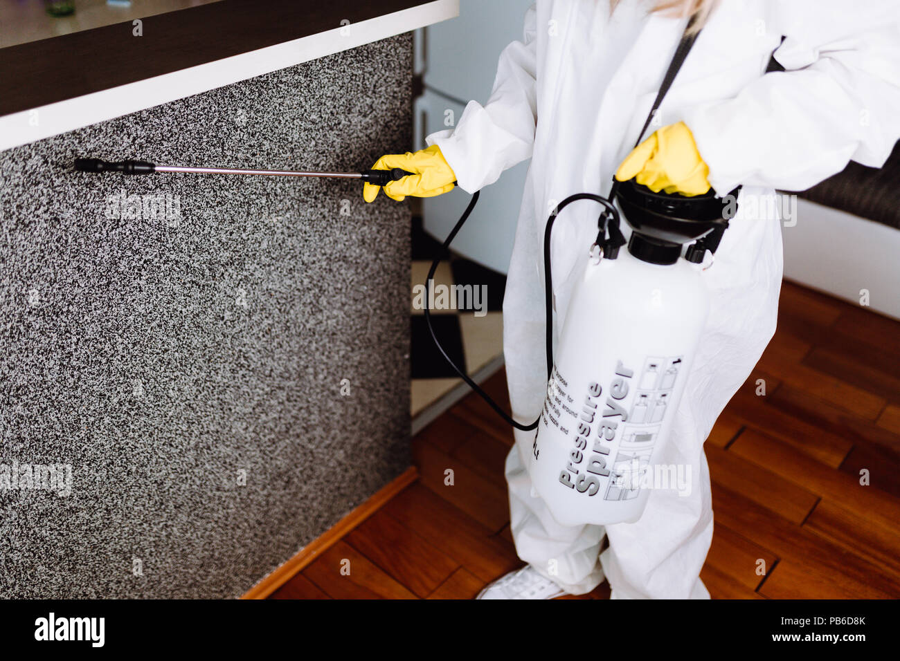Exterminator in work wear spraying pesticide with sprayer. Stock Photo