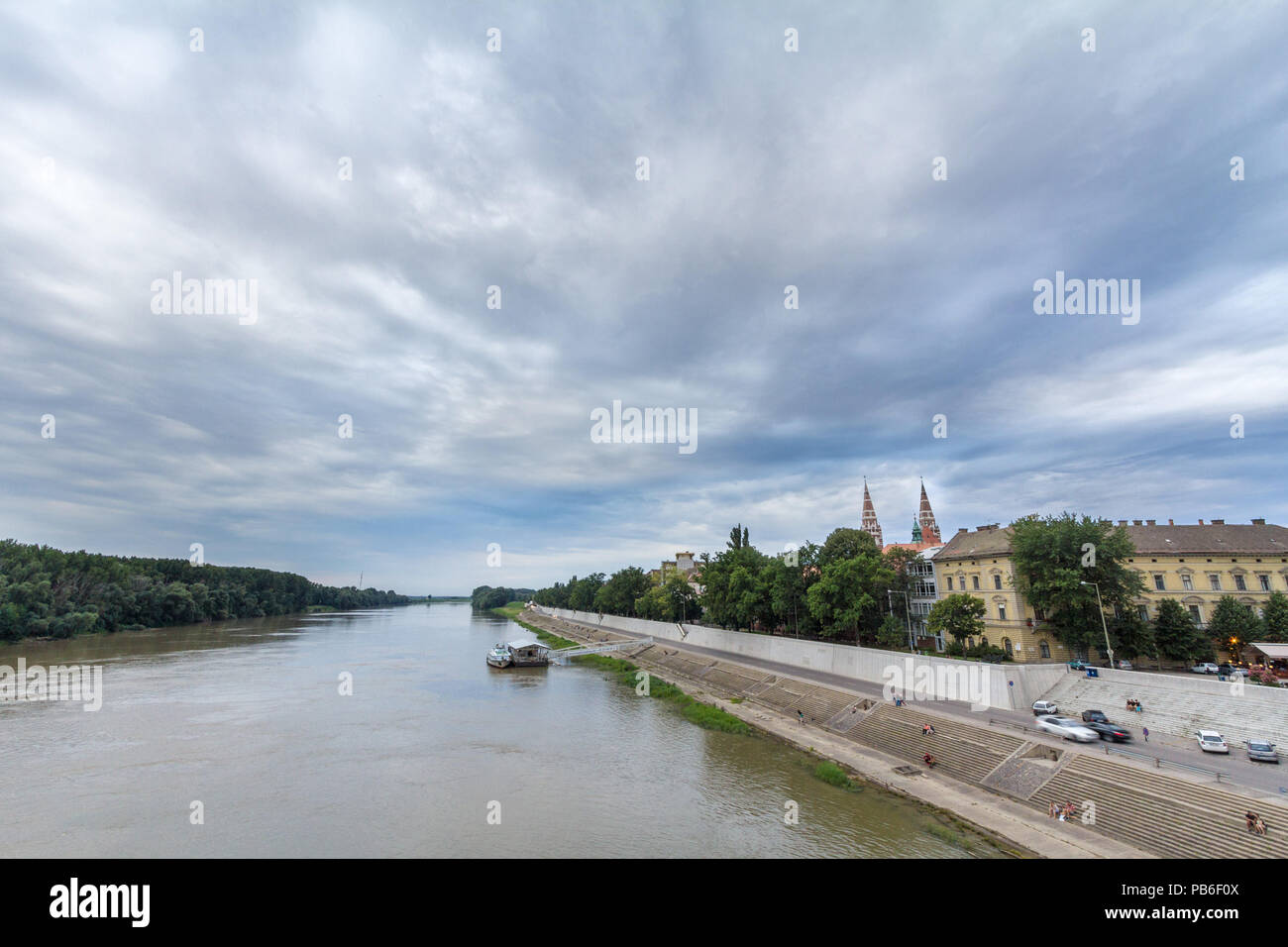 SZEGED, HUNGARY - JULY 4, 2018: Szeged city center seen from Tisza river, with a highlight on Szeged Cathedral, seen into the light during sunset duri Stock Photo