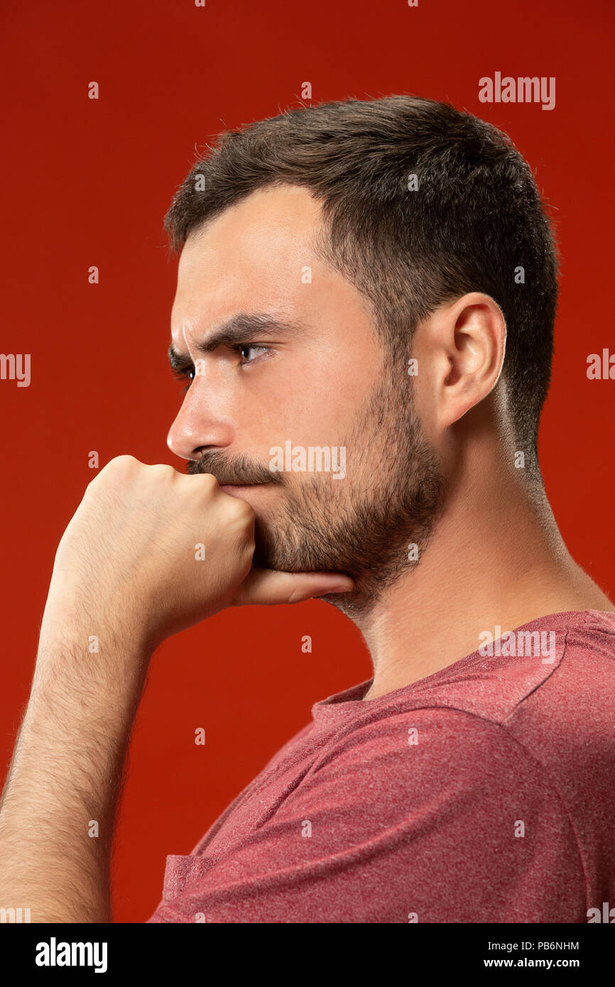 Beautiful man looking suprised and bewildered isolated on red Stock Photo
