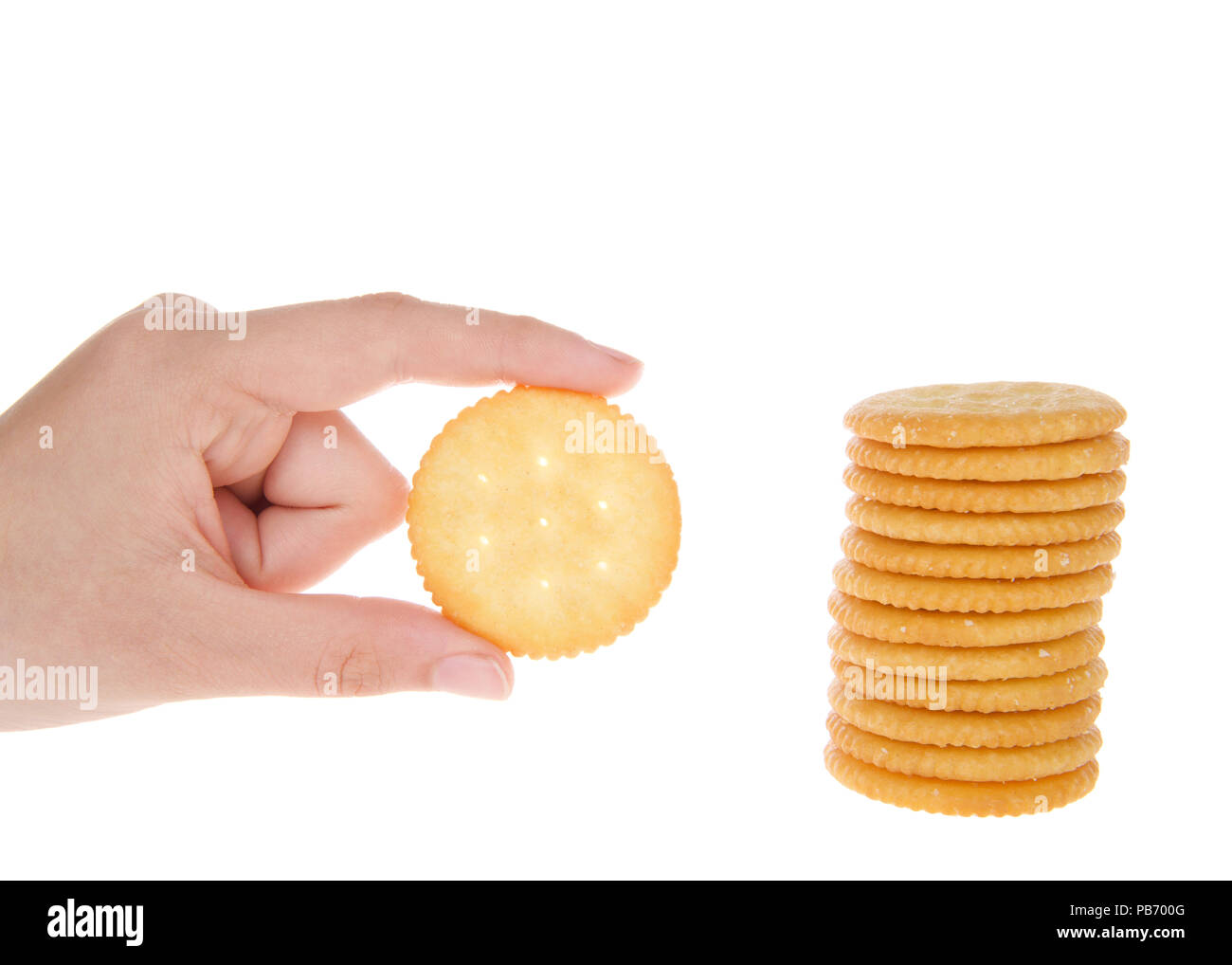 Round salted crackers stacked with young caucasian hand holding a single cracker next to pile. Stock Photo
